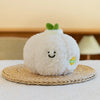 A white soft plush vegetable doll resembling a pear with green leaves, resting on a woven mat.
