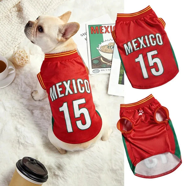 Hundertfarbiger Hund trägt ein rotes Trikot mit der Aufschrift MEXICO 15, neben dem gefalteten Hemd.