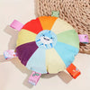 A colorful plush dog toy shaped like a flying disc with a light blue face in the center.