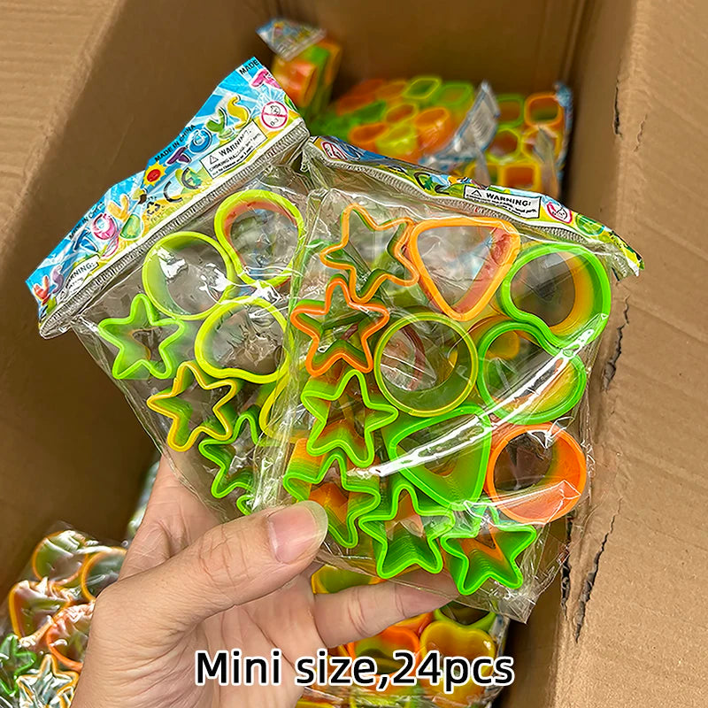 A hand holds a clear plastic bag filled with 24 colorful spring coil toys in various shapes and colors.