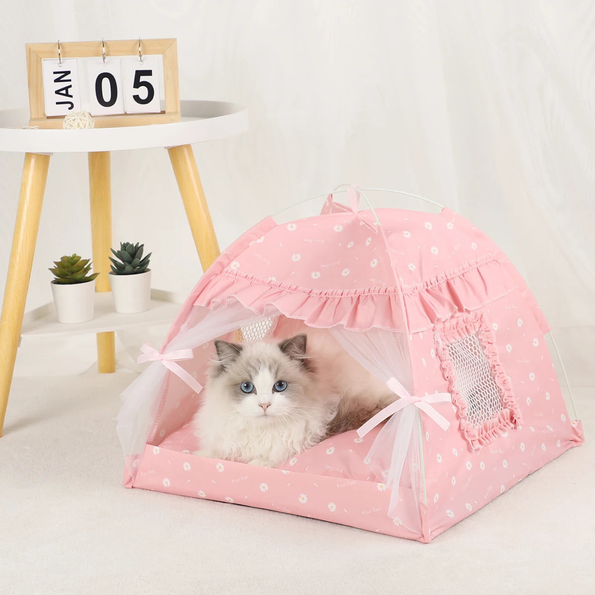Lit pour chat confortable rose avec fenêtre en filet sur une surface blanche.