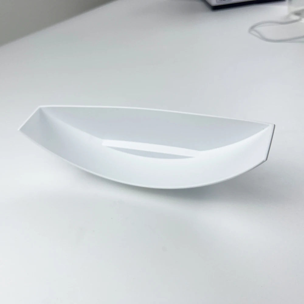 Un cuenco o plato de cerámica blanco y alargado para piezas de repuesto.