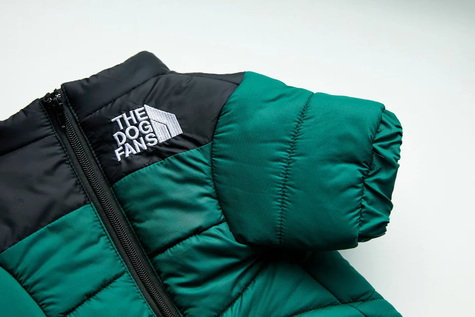 A close-up of a dark green and black quilted dog coat with the text The Dog Fans visible on the chest.