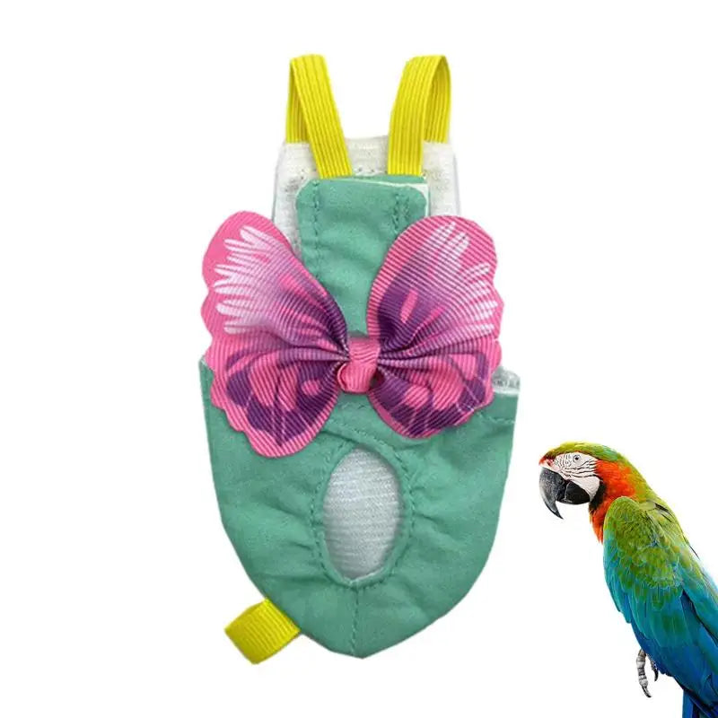 A soft reusable parrot flight suit in green fabric with pink butterfly accents and yellow straps, next to a macaw.
