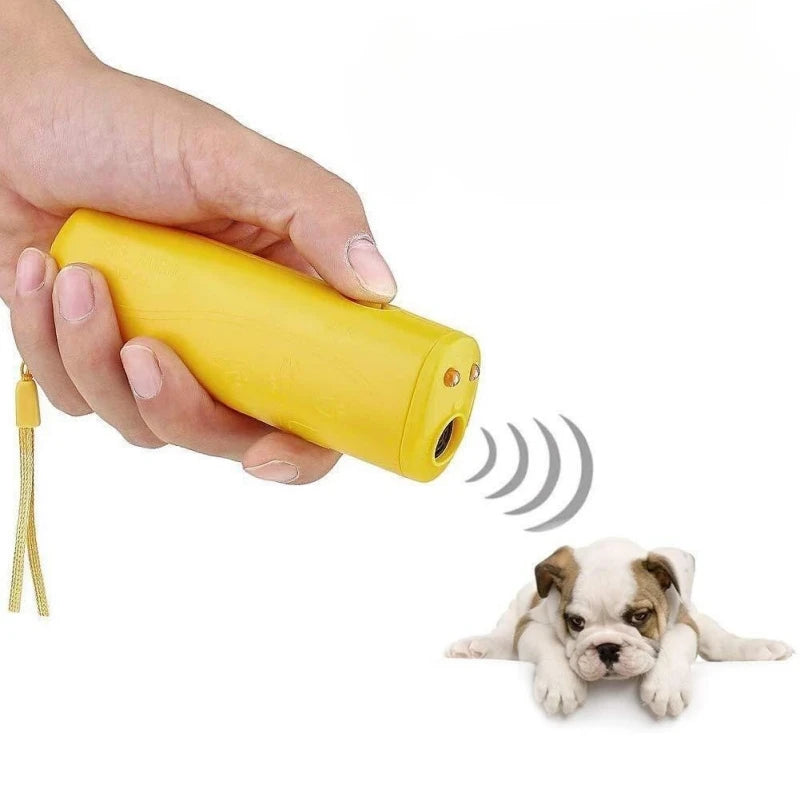 Une main tient un entraîneur canin ultrasonique jaune émettant des ondes sonores vers un chiot.