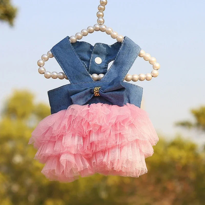 A denim blue bow-neck top and a pink tulle skirt displayed on a pearl hanger.