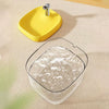 A yellow pet drinking fountain with a metal spout is shown on a light-colored surface.
