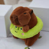 Braune Capybara-Plüschpuppe mit limettengrüner Kapuzenjacke und Flügel, auf weißer Oberfläche.
