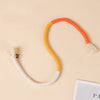 A curved rope toy with orange and yellow sections and fluffy tassels lying on a light background.