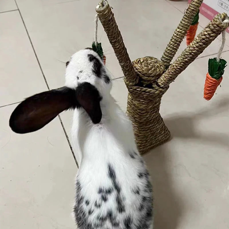 A white and black spotted rabbit toy made from natural grass with carrot decorations.