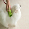 A person is using a green silicone pet hair remover brush on a white dog.