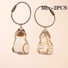 Two glass pendants shaped like cats with gold wire loops for pet hair keepsakes
