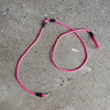 A pink hands-free dog leash with a reflective stripe lying on a gray concrete surface.