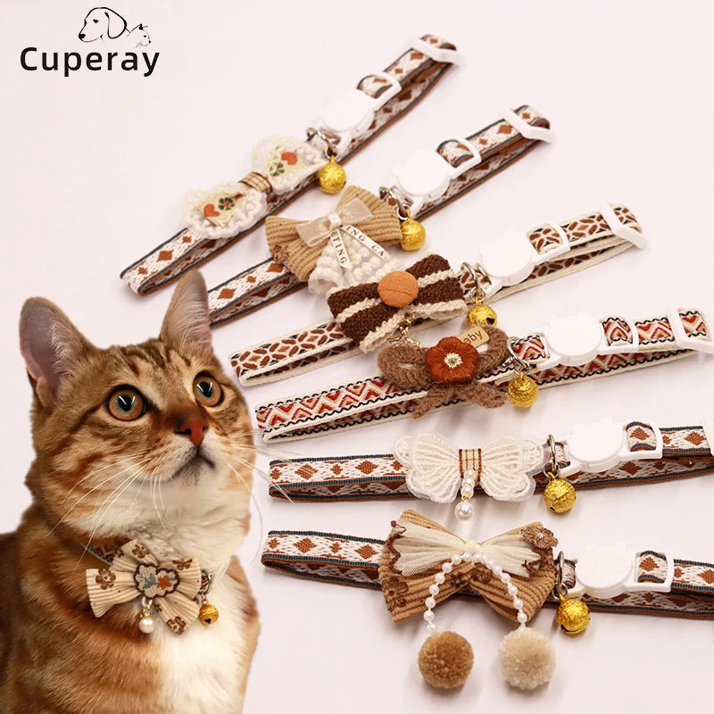 A tabby cat wearing a brown breakaway collar with a bowknot and gold bell.