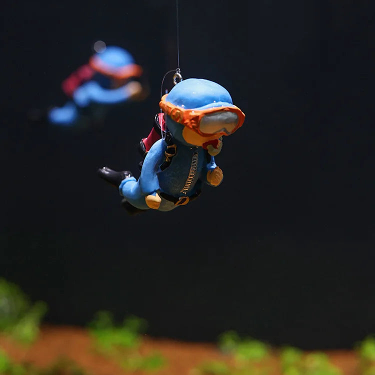 A miniature blue diver figure with an orange mask is suspended in the air against a dark background.