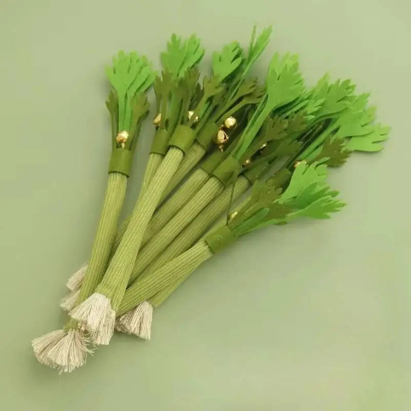 A bundle of green celery stalks with attached bells used as a catnip chew toy