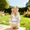 Ein flauschiger brauner Hamster in einem weißen Kleid und einer goldenen Krone in einem sonnigen Garten.