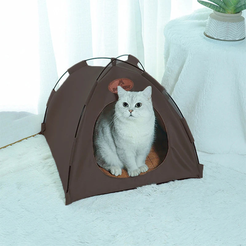 A brown foldable outdoor cat tent with an entrance showing a white cat inside on a white fluffy surface.