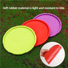 Three brightly colored soft rubber silicone flying discs—lime green, red, and purple—are displayed on green grass.