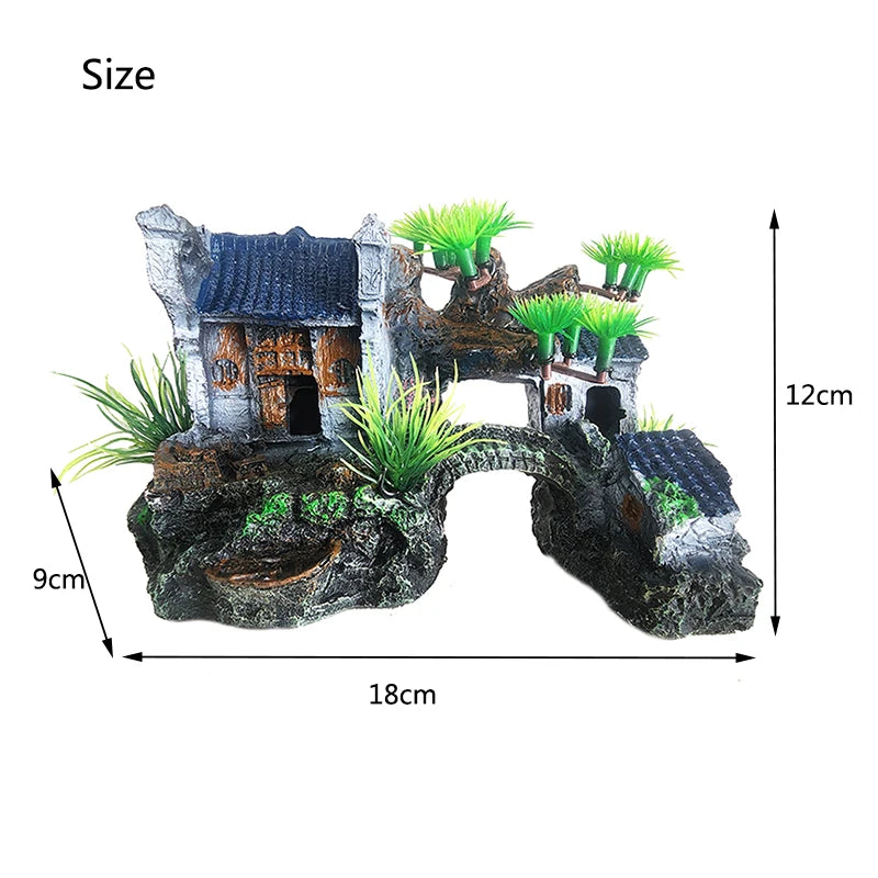 A resin aquarium rockery featuring a cave structure, mossy rocks, and vibrant green aquatic plants.