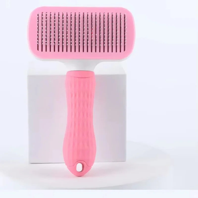 A pink pet slicker brush with a white base is shown against a white background.
