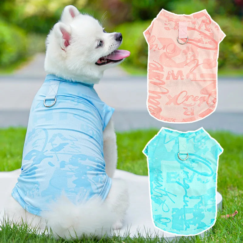 A white dog wearing a light blue ice silk cooling vest outdoors on green grass.