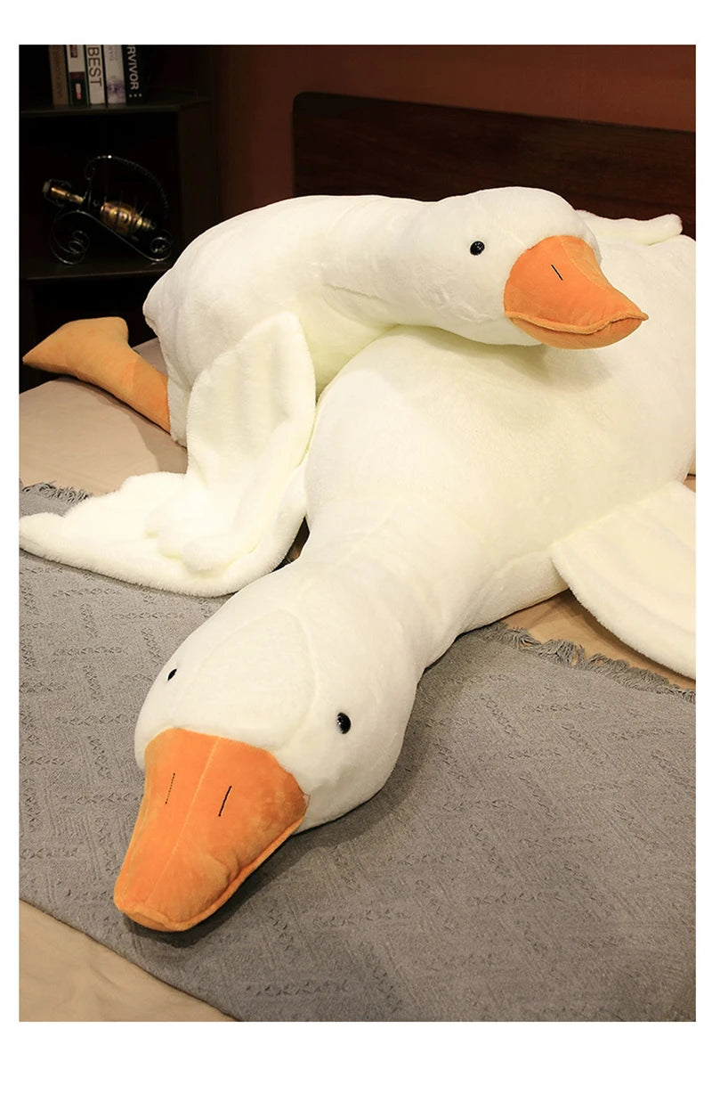 A white plush goose body pillow with an orange beak resting on a gray fabric.
