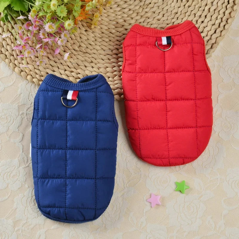 Un manteau de chien rembourré et matelassé bleu marine avec une étiquette rouge et blanche, à côté d'un manteau de chien mate
