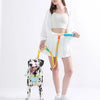 A woman is holding an adjustable hands-free dog leash with a yellow collar and white dog.