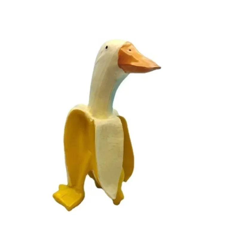 Gelb-cremiges Skulptur eines Enten mit orangebem Schnabel, wie eine Bananenduck.