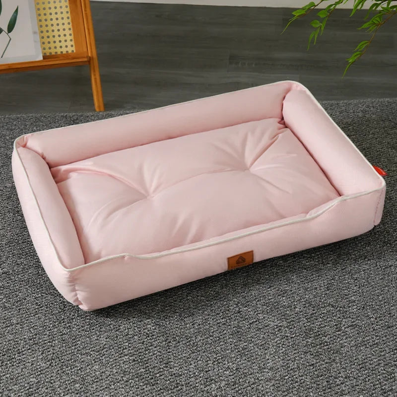 A pink faux fleece pet sofa bed with a waterproof base lying on a gray carpet.