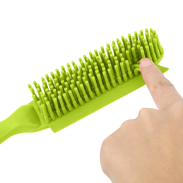 A hand is holding a bright lime green pet hair removal brush with numerous flexible bristles.