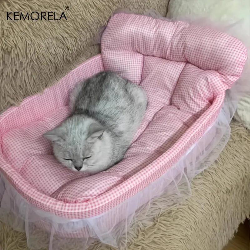 A gray cat is sleeping inside a pink quilted pet bed mat with sheer tulle trim.