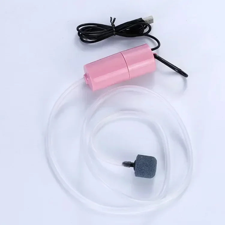 A pink USB-powered aquarium air pump with a clear tubing and a small black accessory.