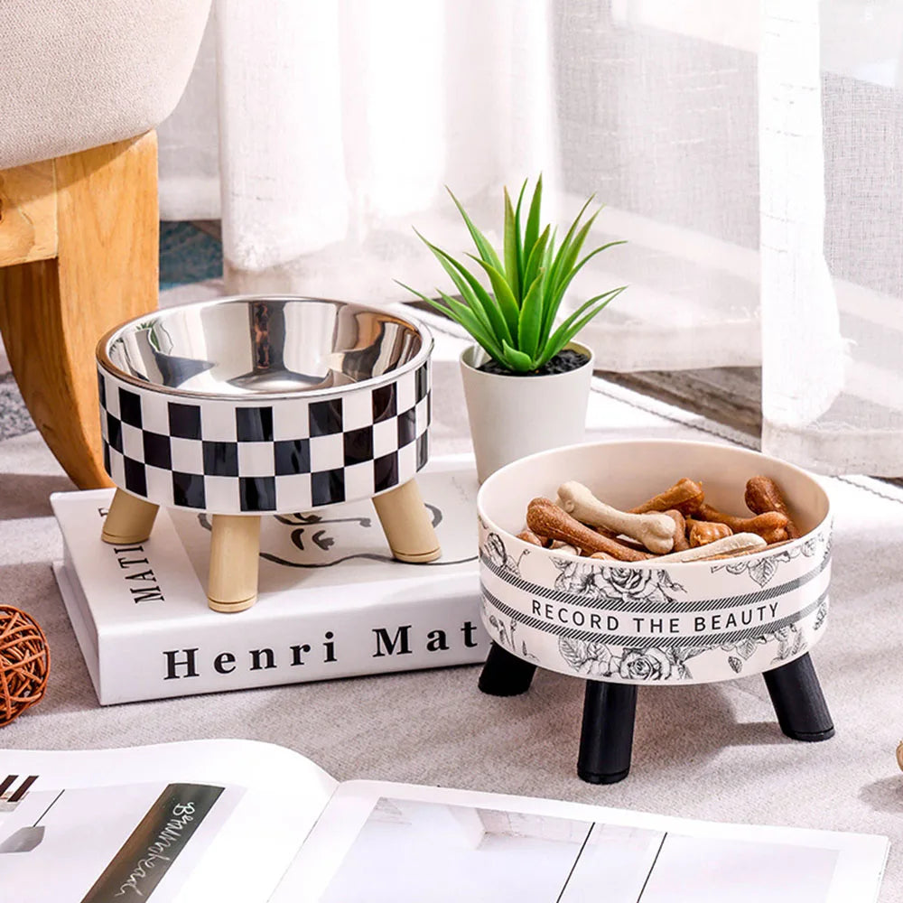 Stainless steel elevated pet bowls with checkered patterns and greenery on a light surface