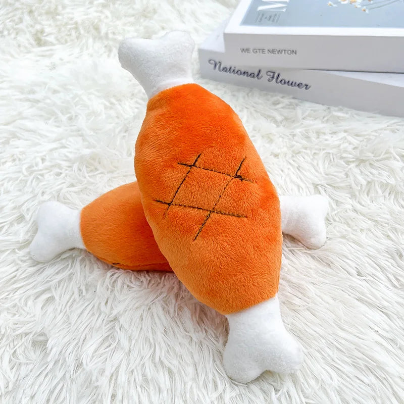 An orange plush duck dog toy with white accents and a stitched pattern resting on a white fluffy surface.