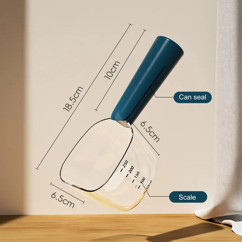 A clear glass measuring scoop and spoon with a blue handle used for pet food measurement.