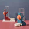 A blue and orange no-drip hanging water bottle for small pets is displayed on a pink surface.