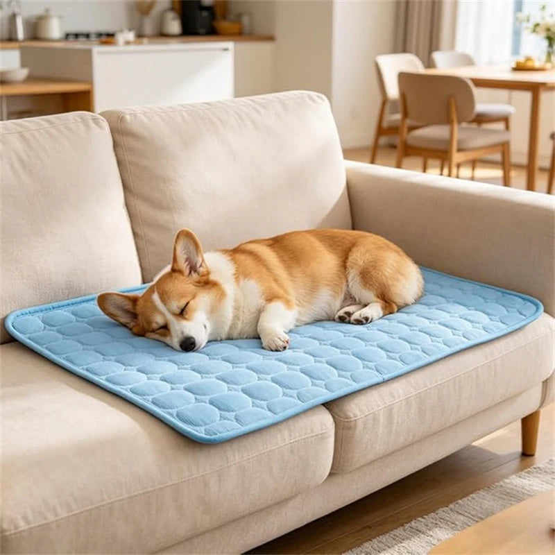 A small orange dog is sleeping on a blue instant cooling pet mat placed on a beige sofa.