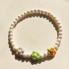 A circular necklace set made of pastel colored beads with small floral accents.