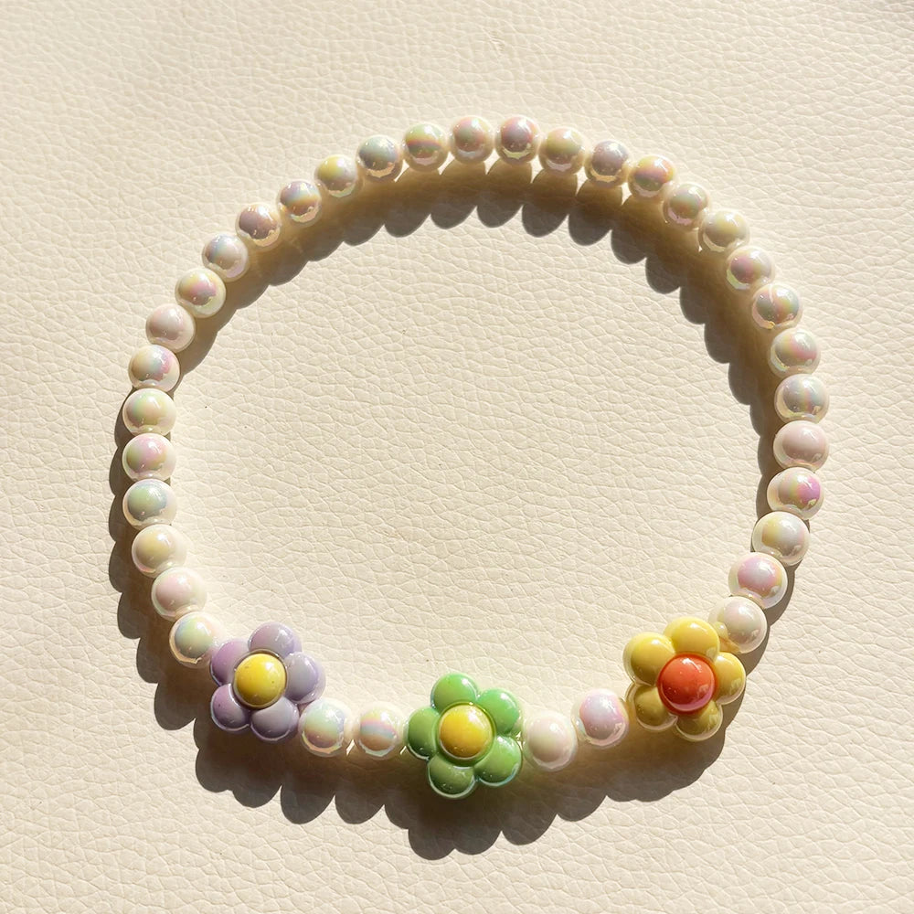 A circular necklace set made of pastel colored beads with small floral accents.