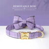 A lavender plaid bowtie dog collar with a gold buckle and engraved nameplate.
