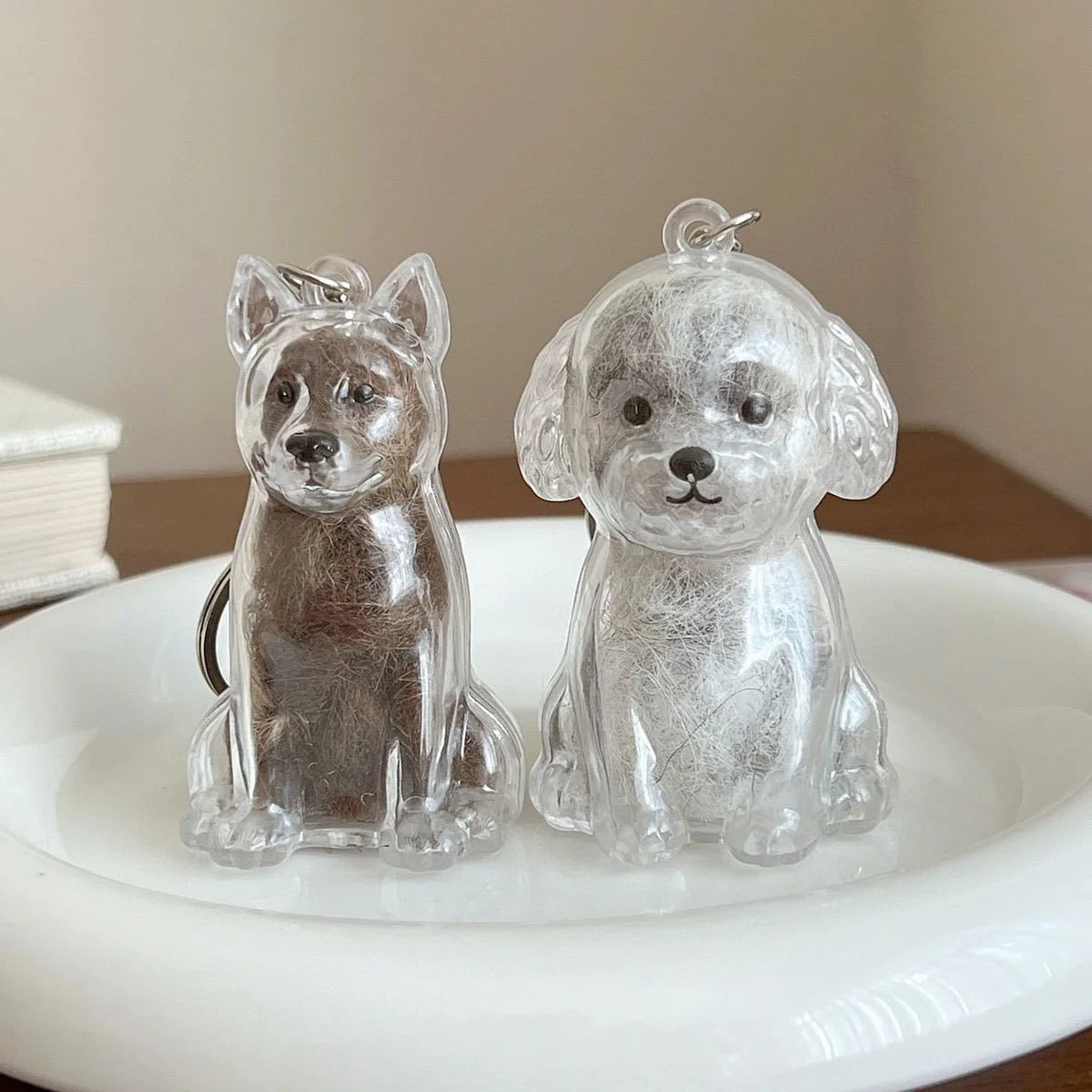 Clear silicone pet hair storage keychain shaped like a dog sitting on a white plate.