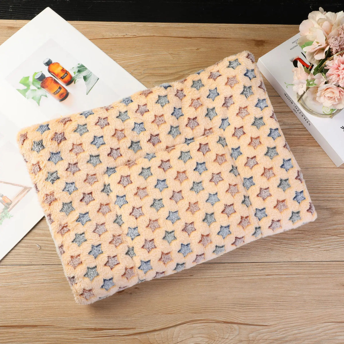Tapis de lit moelleux couleur pêche clair avec motif géométrique bleu, posé sur une surface en bois à côté de fleurs