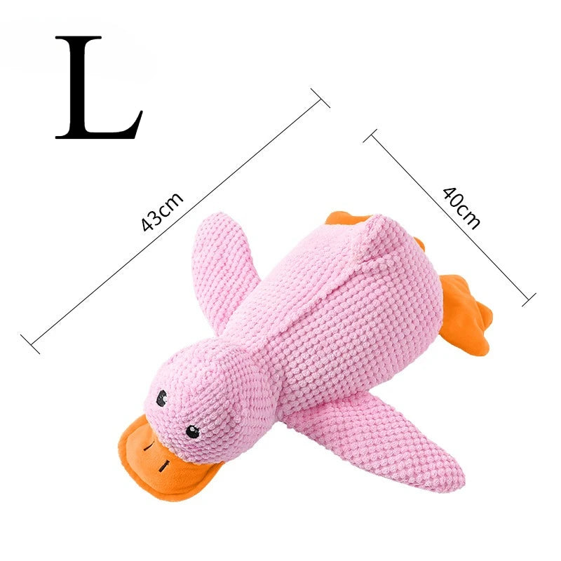 Pink plush duck dog toy with orange accents and a squeaker, shown next to a measurement scale.
