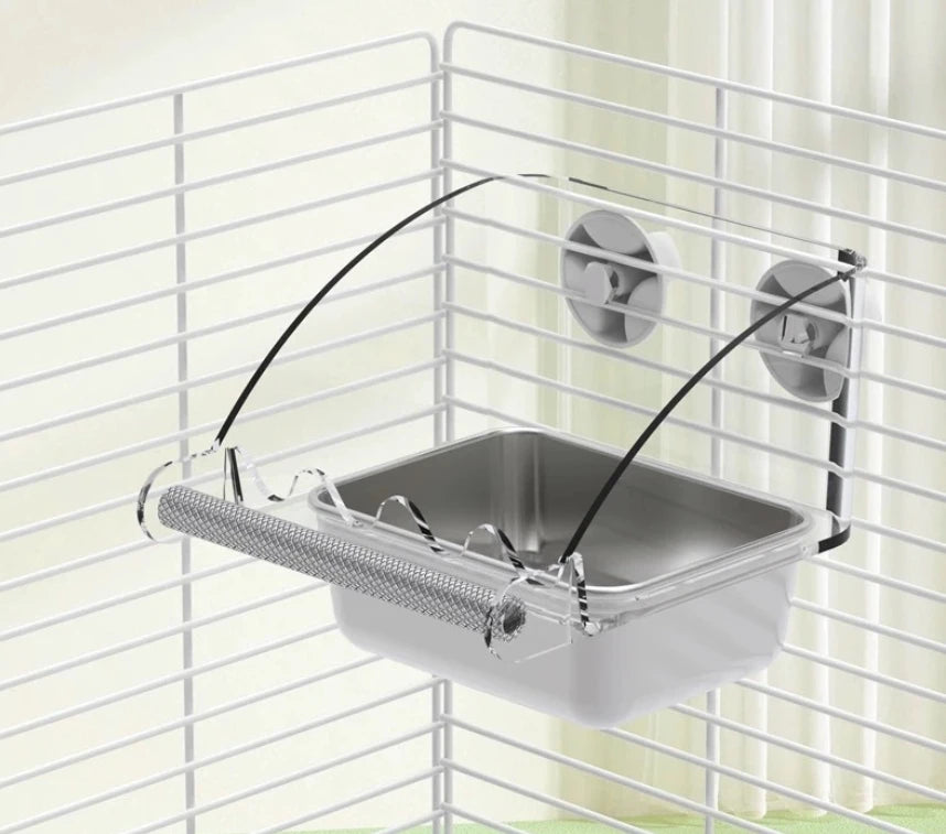 A stainless steel pet feeding bowl is suspended by a wire and mounted on a white grid structure.