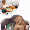 A fluffy orange cat is sleeping inside a gray sofa, with small green and pink cat mice toys nearby.
