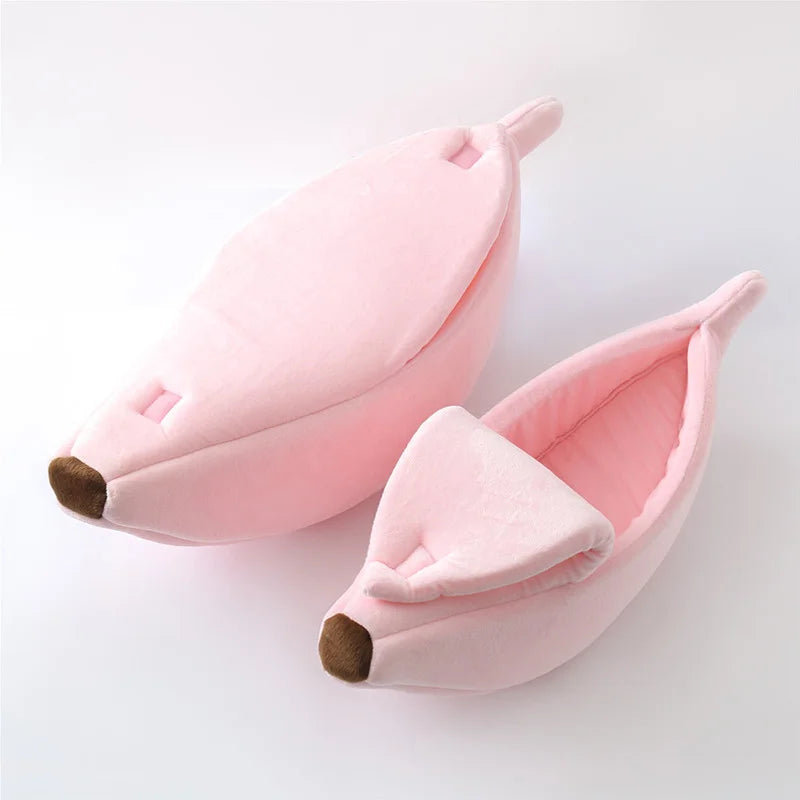 Un lit pour chat en forme de banane rose, fait d'un tissu doux avec des accents marrons.
