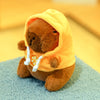 Braune Capybara-Plüschpuppe mit leuchtend orangefarbener Kapuzenjacke und weißen Zierleisten und kleinen Flügeln.