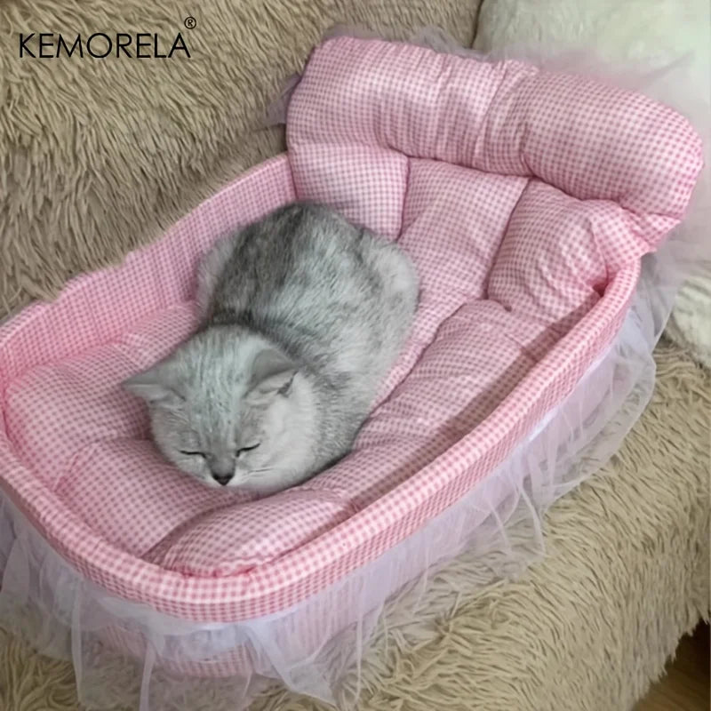 A fluffy gray cat is resting in a pink quilted pet bed mat with sheer tulle trim.